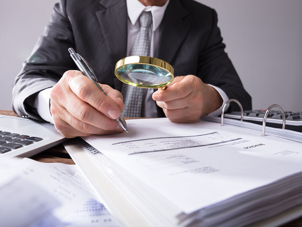 Man examining documents with magnifying glass
